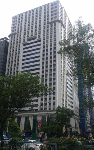 AIC Burgundy Empire Tower has a tall cuboid structure and an exterior of white concrete. The concrete surface has an array of many square recesses where windows can be found. The photograph was taken while standing on the sidewalk of Ortigas Avenue near the Zalameda St. Gate 1 of Corinthian Gardens.