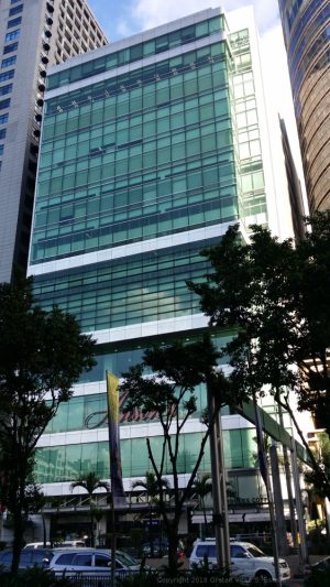 The Anson's Center in Ortigas Center is rectangular with a facade of green glass windows. There are segments of gray concrete that divides the floor, but the higher floors have fewer of these concrete segments and more of the glass surface. The word Anson's in red signage is between the second and the third concrete segment from the ground.