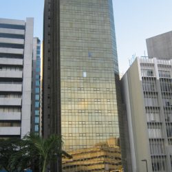 First E-bank Tower is a tall narrow building with a facade that is made entirely of brownish-green glass panels.