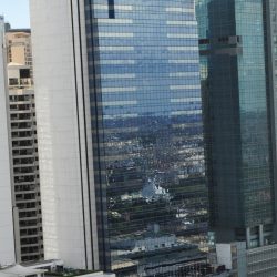 BPI Buendia Center has a tall rectangular prism shape with a trapezoidal prism on top. It features a concrete facade on the side face and a front face covered in dark glass panels. This picture was taken from the fifteenth floor of Citadel Inn Makati.