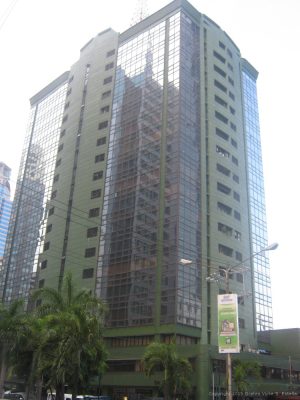The Centerpoint Building is a tall cuboid structure with a facade of green-painted concrete and dark glass panels. This photo was taken while standing on the sidewalk along Julia Vargas Avenue.