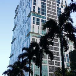 Cyberpark Tower One has a tall cuboid shape, with a surface of mostly white concrete with small blue-green glass windows. The shot was taken while on a pedestrian lane along Gen. Aguinaldo Ave. across Novotel Manila Araneta Center.