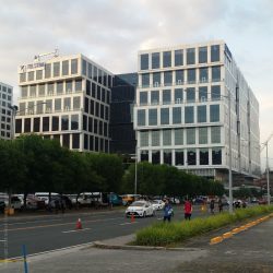 Five E-com Center has rows of rectangular glass pane windows. The middle and the top floors are protruding from the rest. This is the view from Palm Coast Ave. cor Pacific Drive. It has rows of rectangular glass pane windows. The middle and the top floors are protruding from the rest.