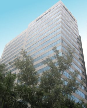 Global One Center is a tall cuboid structure with an exterior of alternating bands of glass panels and gray concrete. This is the building, as seen from the segment of Eastwood Palm Tree Ave. between E-commerce and Citywalk 1.
