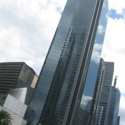 GT Tower has an angular design with sharp angles and diagonal patterns. Its exterior is covered in blue glass panels, and the top has triangular fins, giving it an obelisk-like appearance. Photo taken from the sidewalk at the corner of Ayala Avenue and Amorsolo St.