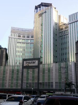 Back of Insular Life Building: the upper floors have a metallic gray facade of vertical strips with narrow windows between them. This is the view from Valero St. parallel to Valero Access Road 3 near Sedeño St.