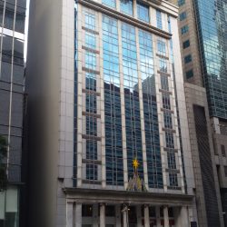 The KPMG Center is a white concrete structure with vertical glass panels across several floors and Greek columns at the ground floor.