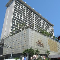 Manila Pavilion Hotel is an L-shaped building with gray concrete facade. This picture was taken from the opposite corner at the intersection of UN Ave. and Maria Y. Orosa St.