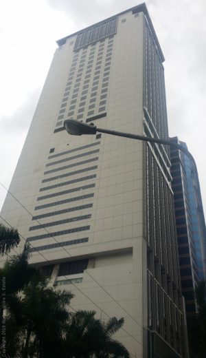 Marco Polo building is a very tall rectangular prism structure with a concrete exterior and few windows on the side. This is Marco Polo, as seen along Sapphire Road across Ortigas Building.