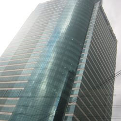 MDC 100 is a cuboid structure with a cylinder inserted in one corner. The cuboid has alternating rows of concrete and glass, while the cylinder's facade is all glass panels. The picture was taken from the lower staircase levels on the other side of E. Rodriguez Ave. The staircase is the access to the footbridge connecting both sides of E. Rodriguez.