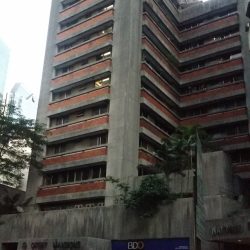 The Orient Mansion is a low-rise and L-shaped building with a concrete and brick facade. The main entrance has a protrusion above it on which the words ORIENT MANSION are attached.