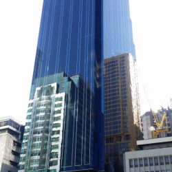 The Orient Square is a tall cuboid building with a facade of blue glass panels and maroon marble tiles. This is Orient Square, as seen from the parking between Emeral Avenue and Garnet Road near Julia Vargas Ave.