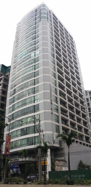 The Pacific Center has glass panels with a white concrete facade on all floors except the two lowest stories. This picture shows the view from the sidewalk on the other side of San Miguel Ave.