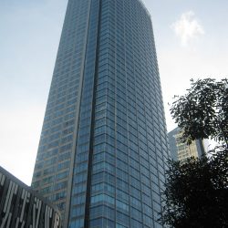 Tall skyscraper with a blue glass facade and a slender, rectangular shape.