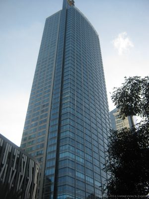 Tall skyscraper with a blue glass facade and a slender, rectangular shape.