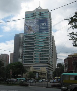 The Philippine AXA Life Center has an exterior made of horizontal bands of glass and white concrete. It also has a pyramidal steel spire on top. The picture was taken from the sidewalk at Malugay St. cor. Ayala Avenue.