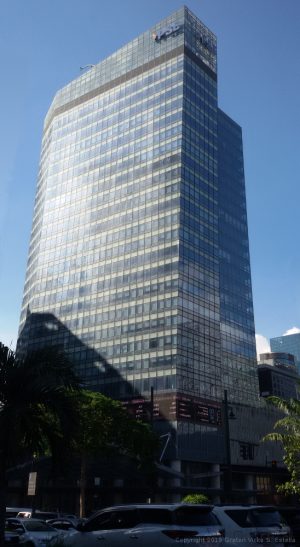The Philippine Stock Exchange Tower is an L-shaped building with a blue glass facade.