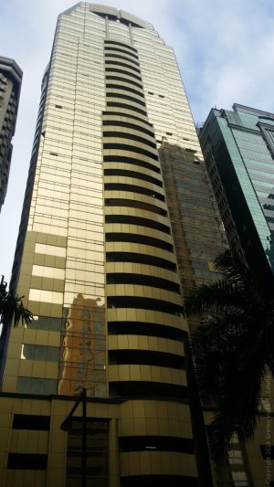 Raffles has a gold/bronze-colored exterior covered with glasses and has a balcony in the middle of each floor.