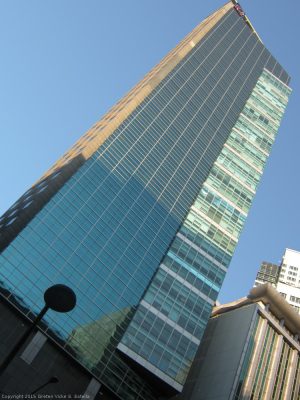 Robinsons Summit Center has tall rectangular shape, with a smaller triangular prism extension and a facade of teal glass panels. Picture of Robinsons Summit Center taken from the sidewalk in front of Security Bank Centre on the other side of Ayala Avenue.