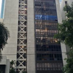 The Sagittarius Building is a gray mid-rise building. As seen in front, it has two parts. What appears to be the main section on the right is full of dark glass windows, with 7-11 and Subway at the ground floor.