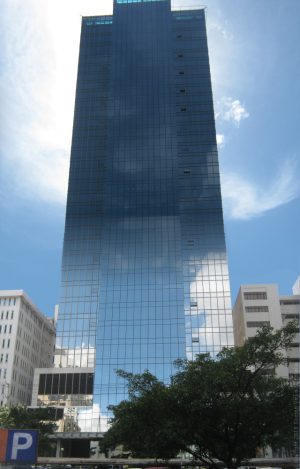 Tower 6789 is covered with glass panels and has an almost rectangular prism shape if not for the protrusion near the top. Shown here is the backside of Tower 6789, as seen from Valero St.