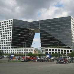 Two E-com Center looks like a giant short pants with black glass and white concrete facade. This picture is as seen from the other side of the open parking space next to it along Seaside Boulevard near Palm Coast Ave.