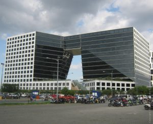Two E-com Center looks like a giant short pants with black glass and white concrete facade. This picture is as seen from the other side of the open parking space next to it along Seaside Boulevard near Palm Coast Ave.